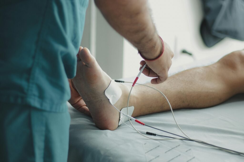 Close-up of a healthcare worker examining a patient's foot with medical equipment in a hospital setting.