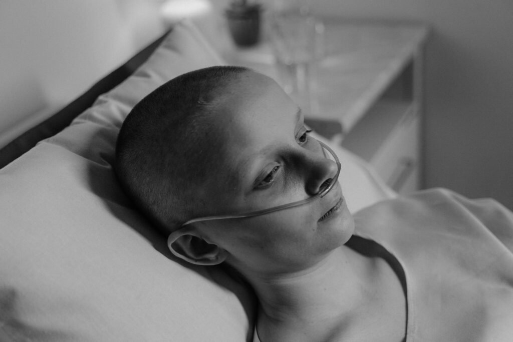Black and white image of a woman patient in a hospital bed with a nasal cannula.